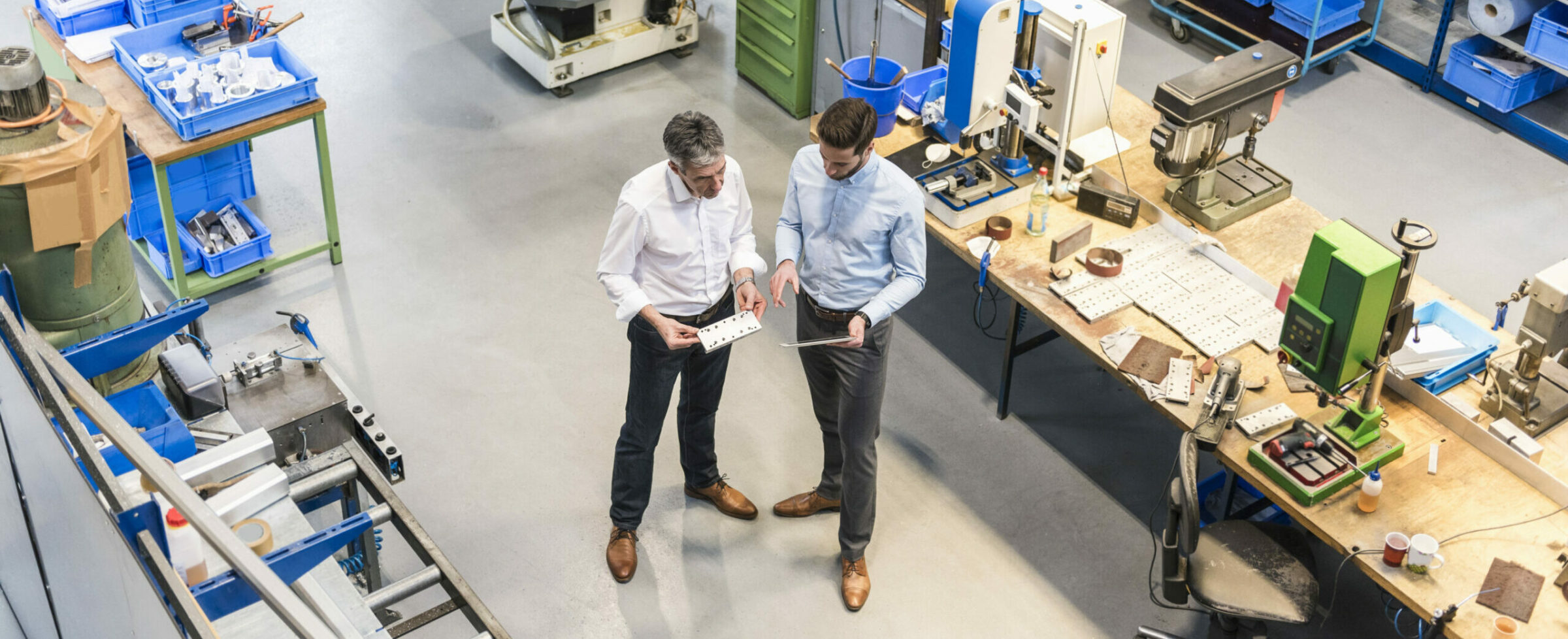 Two men in discussion looking at an iPad in a lab or production environment